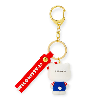 Enhance your keys with the Hello Kitty 3D Figure Keychain. It features a charming Hello Kitty dressed in blue with striped sleeves and a red tag displaying "Hello Kitty" in white. Includes a gold key ring and clasp for easy attachment.