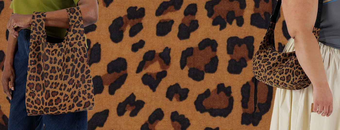 Two people holding leopard print tote bags against a leopard print background.