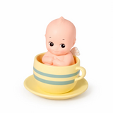 Kewpie baby figure in striped teacup, pale yellow cup and saucer