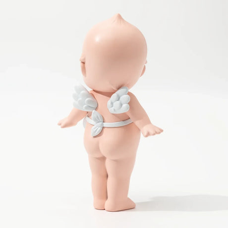 Back view of naked baby doll figurine with small white wings strapped on its back against white background