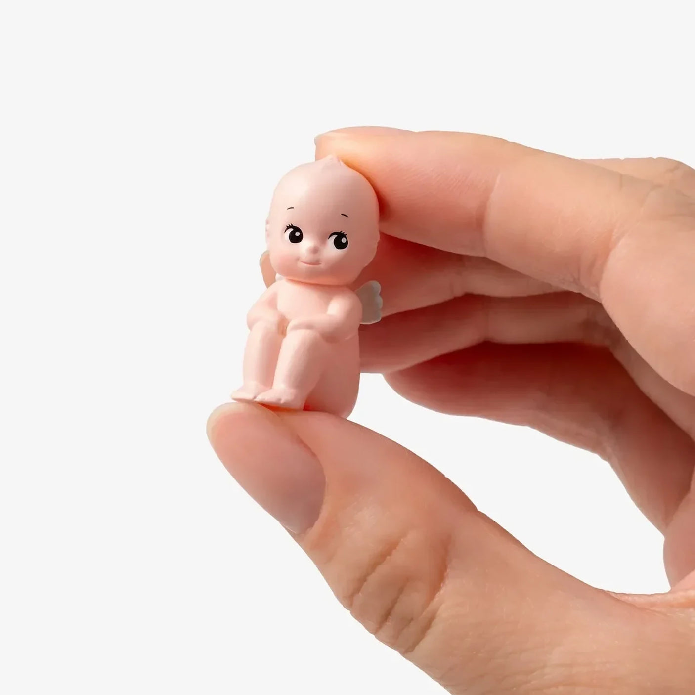 Mini baby figure with pink body and black eyes, held in a hand