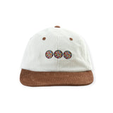 White corduroy cap with brown brim and three colorful beaded circle designs embroidered on front panel