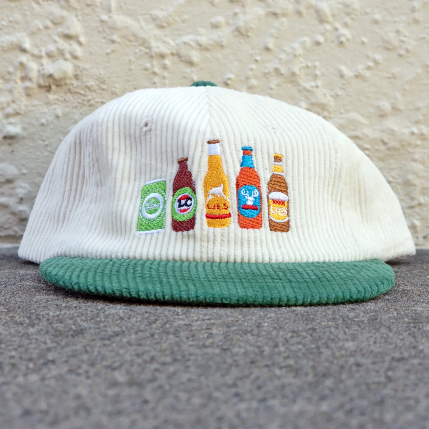 White corduroy cap with green brim and beer bottle front embroidery