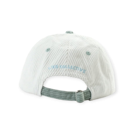 Off-white corduroy cap back view featuring light green adjustable strap and light blue embroidered Lies Collective text
