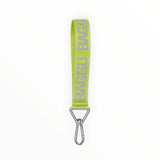 The Baggu Logo Keychain - Citron, crafted from recycled nylon in green, features a chic design with the distinctive Baggu logo and a sturdy metal clip at the bottom.