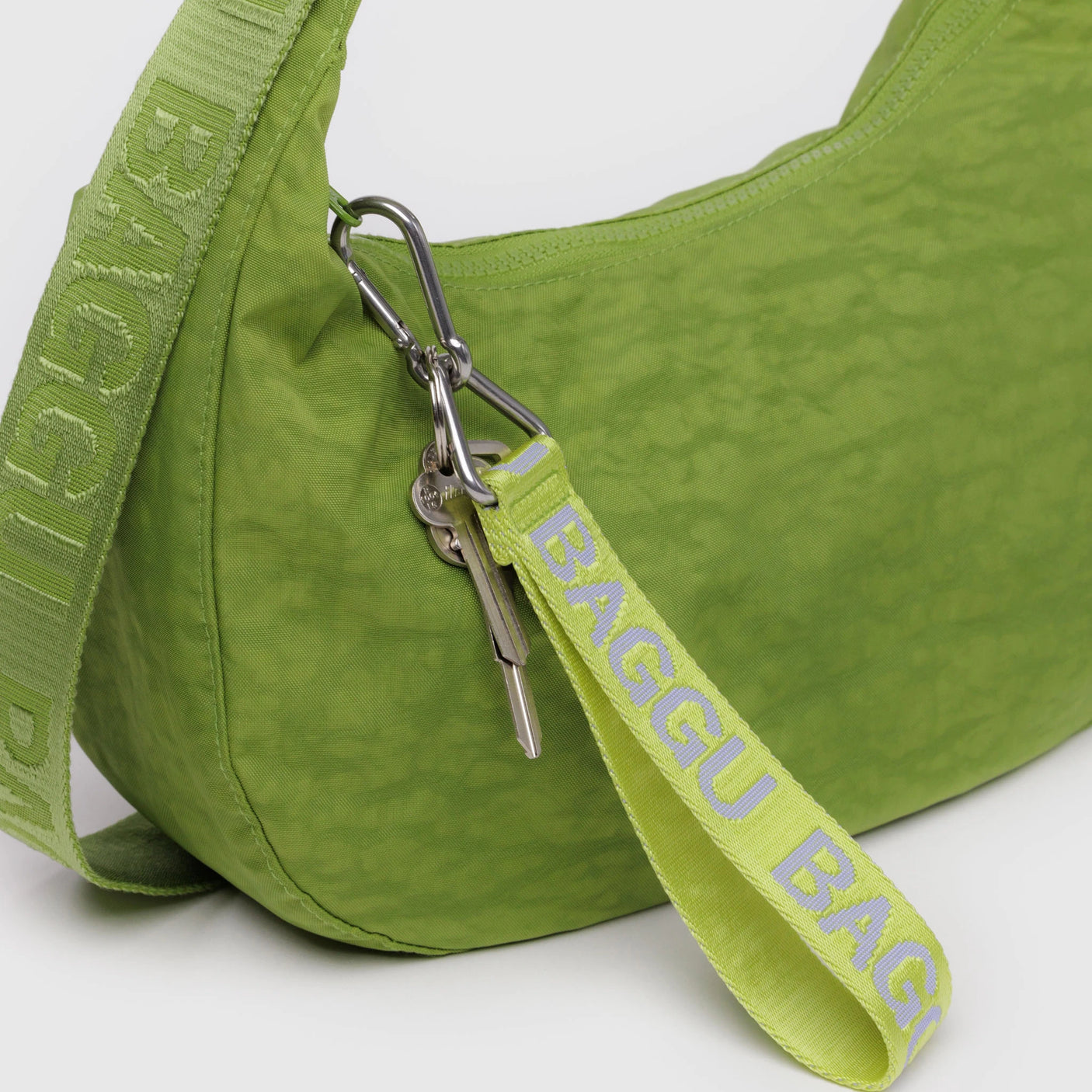 A green BAGGU handbag with a matching strap, made from recycled nylon, features a Baggu Logo Keychain in citron that dangles elegantly from the strap.