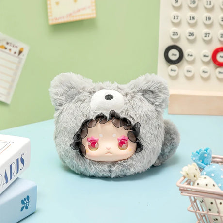 Gray plush Lovely Emma Rua Rua Zoo bag charm with pink star-shaped eyes and black curly hair on blue desk background
