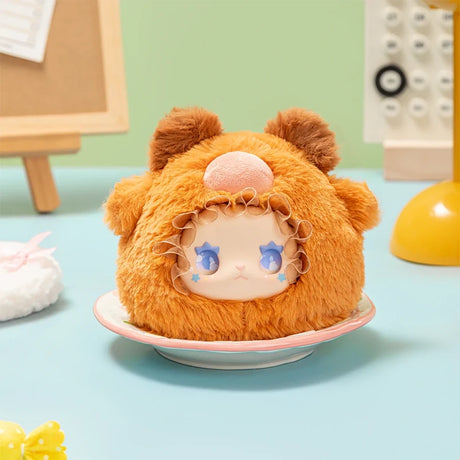Plush Lovely Emma Rua Rua Zoo bag charm in fuzzy orange bear costume with blue star-shaped eyes on pastel tabletop