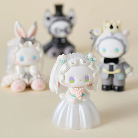 Four stylized animal figurines from Lucky Emma's "Secret Forest Wedding" blind box series are displayed. The front figure is in a white dress holding pink flowers, with three others in diverse attire blurred behind. Each hand-painted piece adds whimsy and charm.