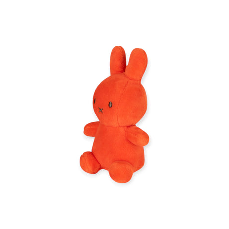Side view of compact coral Mini Miffy Lucky Charm plush seated against white background