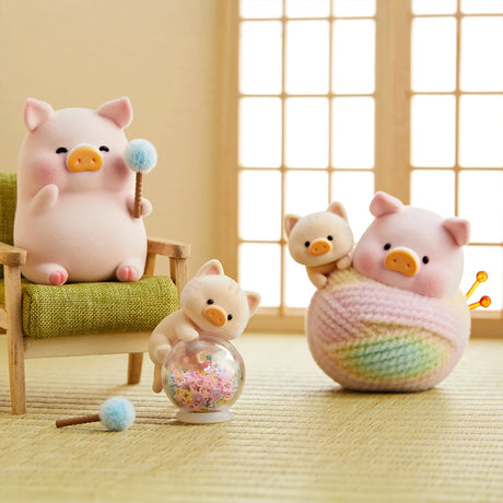 LuLu the Piggy figurine with cat costume holding a blue pompom near small cat figures on tatami mat indoors