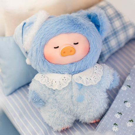 Plush LuLu Piggy keychain dressed in soft blue fuzzy pajamas with lace collar and matching sleep cap on cozy bed setting