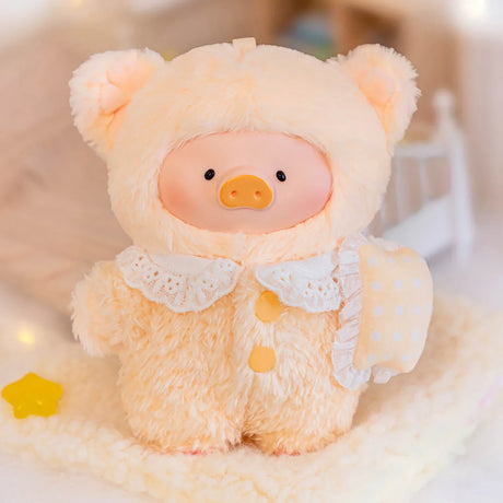 Plush LuLu Piggy wearing fluffy cream pajamas with lace collar holding a polka dot sleep mask on cozy blanket