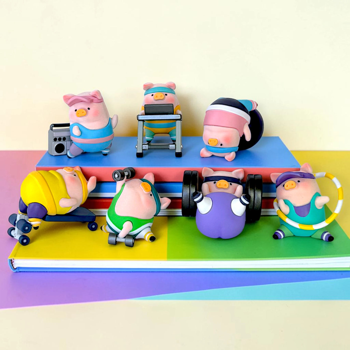 LuLu The Piggy - Fitness Club Blind Box with seven colorful pig figures exercising on stacked books by LuLu The Piggy