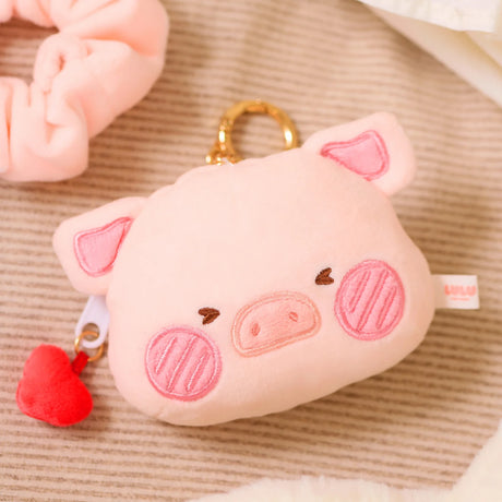 Plush pink pig-shaped pouch bag charm with embroidered face, gold keyring, and small red heart zipper pull accessory