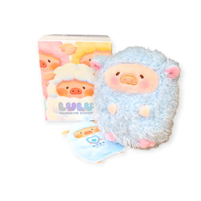 A plush toy of LuLu the Piggy as a blue sheep stands beside its pastel Rainbow Sheep Plush Blind Box from LuLu The Piggy and a matching cardboard cutout featuring the same character.