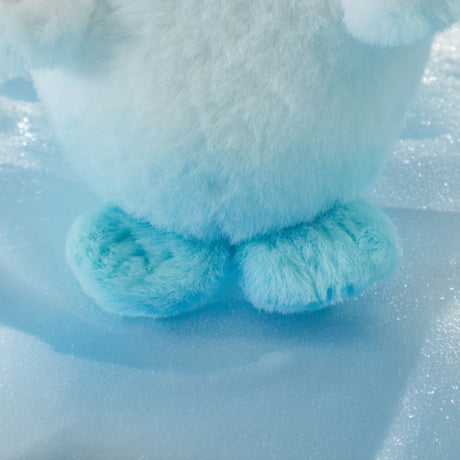 Close-up of a LuLu The Piggy - Baby Seal LuLu Plush keychain in light blue, standing on a textured, frosty surface with its lower body and two rounded feet visible.