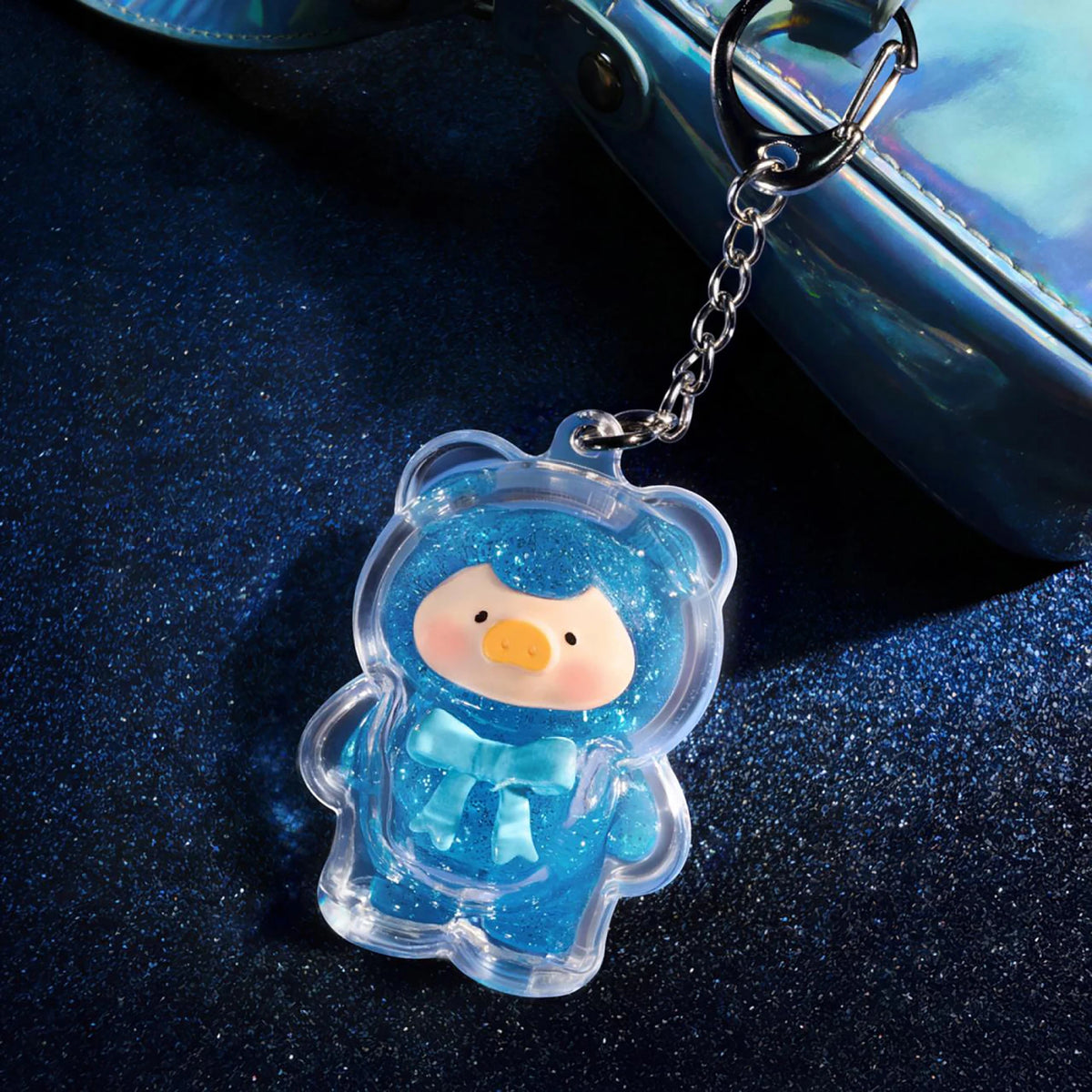 Clear blue teddy keychain charm with pink face and small blue outfit