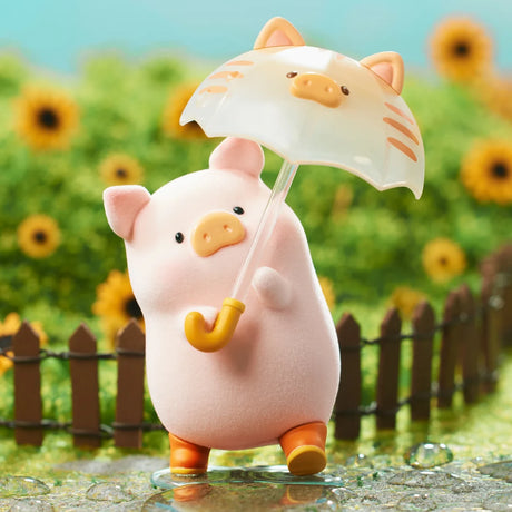 Pink LuLu the Piggy figure holding a cat-themed umbrella standing on a wet path with sunflowers and wooden fence background