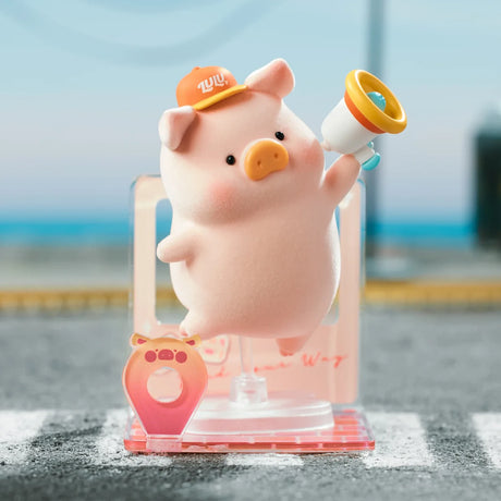 Pink LuLu the Piggy figure wearing an orange hat and holding a megaphone on a clear acrylic stand outdoors