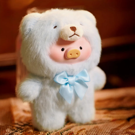 The LuLu The Piggy brand's Teddy LuLu the Piggy Plush Pal - Blind Box features a piggy face in a light blue teddy bear onesie with a blue ribbon bow, standing on a patterned surface.