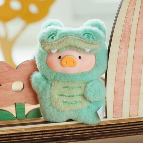 A LuLu The Piggy plush dressed as a green crocodile stands by a wooden flower and surfboard—an ideal collectible from the Lulu The Piggy - Animal Party Puppet Keychain Blind Box for fans and collectors alike.