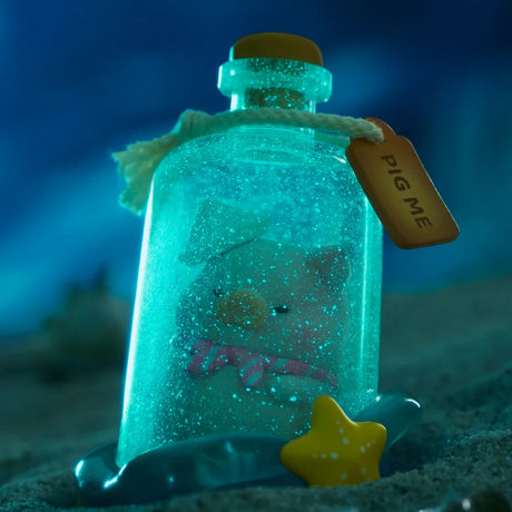 A small LuLu The Piggy figurine with a pink scarf sits in a glowing "PIG ME" bottle on sand beside a yellow star, from the LuLu The Piggy - Ocean Blind Box series.