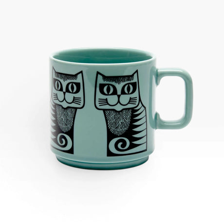 Teal ceramic mug with two black-and-gray cat faces and striped tails
