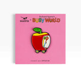 Enamel pin of red apple on pink Richard Scarry's Busy World card