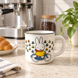White ceramic mug with Miffy rabbit riding a bicycle, flower print on front