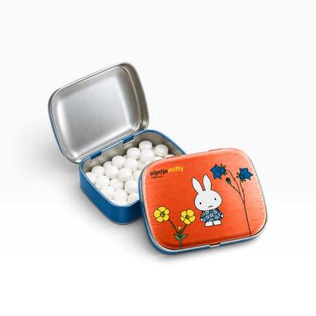 Open blue pill tin with white balls and orange lid featuring Miffy with flowers