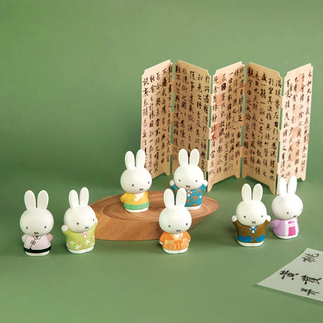 Seven Miffy figures dressed in colorful ancient-style outfits displayed with traditional calligraphy screen on green background