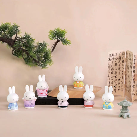 Seven Miffy figures in pastel ancient-style costumes displayed with bonsai and calligraphy scrolls on soft beige background
