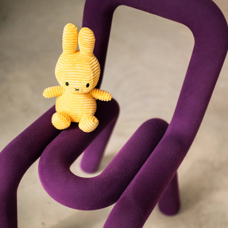 The Miffy Bunny Plush Corduroy - Buttercream 23cm from Miffy snugly fits on a distinctly shaped purple chair with hypoallergenic fabric.