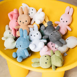 A charming assortment of Miffy Bunny Plush toys in vibrant colors, crafted from recycled polyester, comfortably situated in a yellow container.