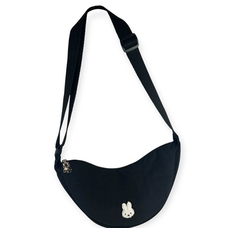 Black Miffy Crescent Crossbody Bag hanging to show curved silhouette and silver zipper charm, gallery image 1