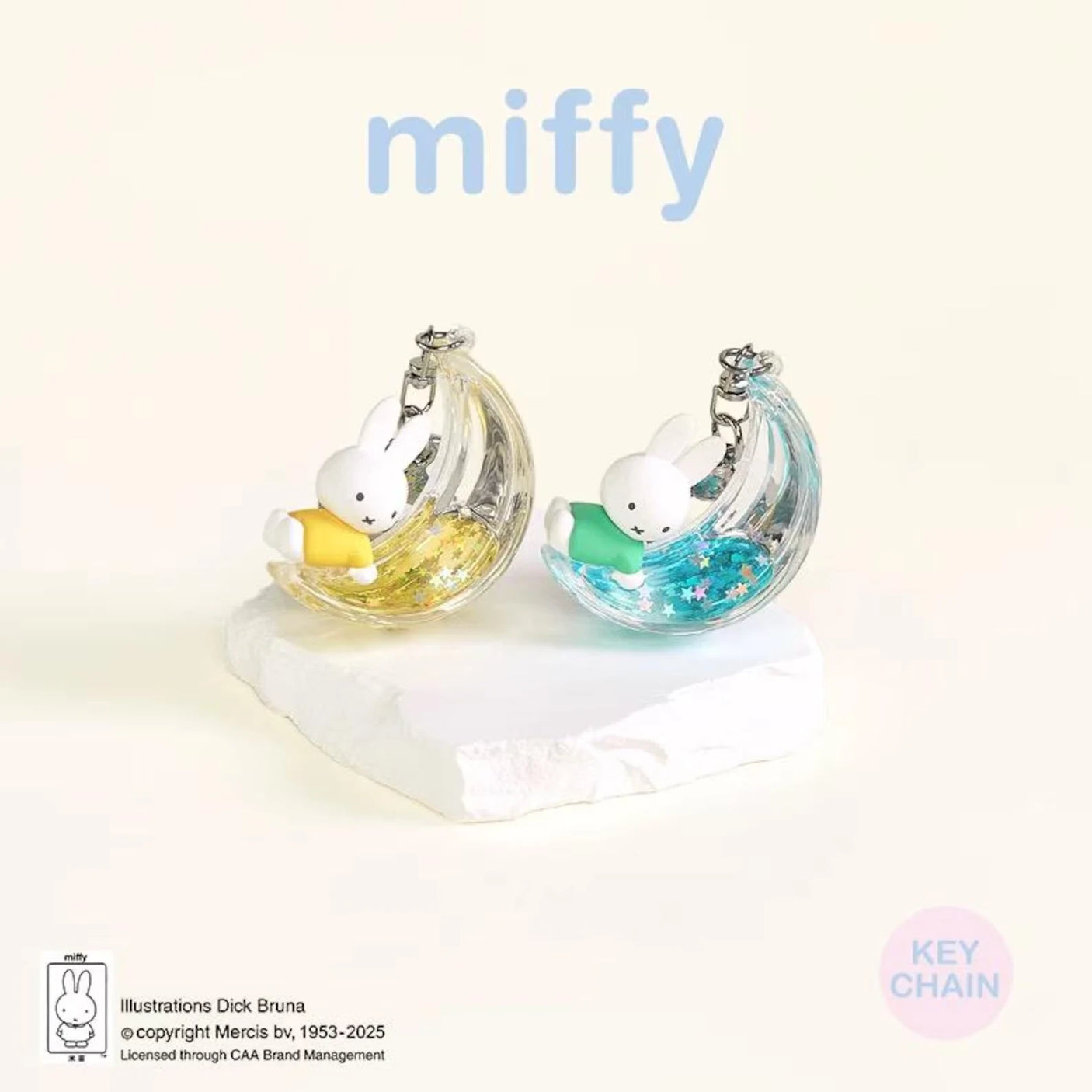 Two rabbit moon keychains with iridescent silver shells and pastel yellow and blue charms