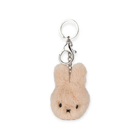 The Miffy Fuzzy Keychain - Beige, by Miffy, includes a fluffy beige bunny with a silver key ring and clasp, made from sustainably soft materials.