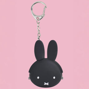 Black Miffy keychain coin pouch made of silicone with a silver clasp against a pink background