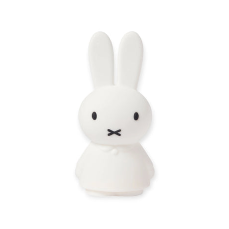 A cartoon character resembling a rabbit, featuring long ears and a minimalist face, stands facing forward, much like the Miffy Shines - Night Light (22cm) by Miffy with touch-sensitive dimming for customizable brightness.