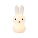 The Miffy Shines - Night Light (22cm) by Miffy is a charming rabbit-shaped lamp with a minimalist design, offering touch dimming features and equipped with a rechargeable battery. Its two long ears and small round body add an enchanting touch to any room.