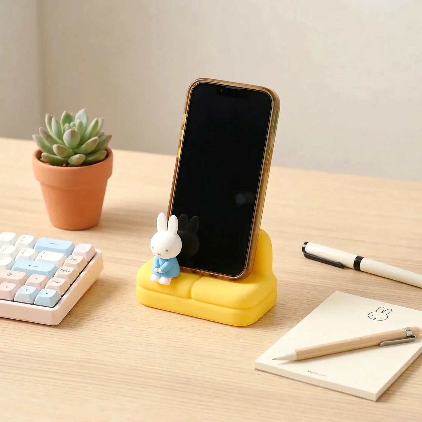 Yellow mini sofa phone stand with Miffy figure holding a smartphone