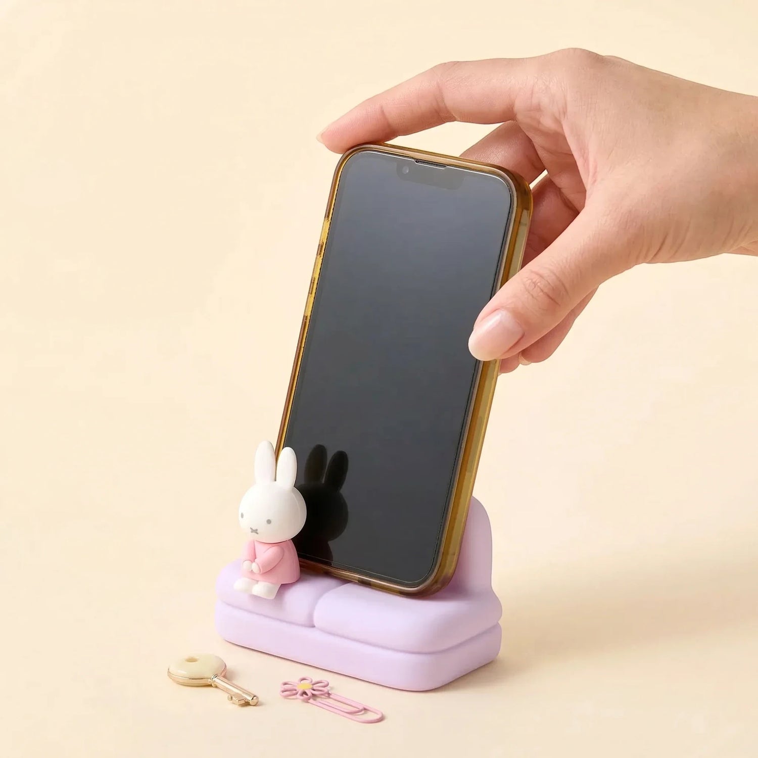 Purple mini sofa phone stand with Miffy figure, smartphone in the holder