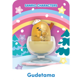 Gudetama lounges in a dessert cup against the vibrant Mighty Jaxx Sanrio Snowy Dreams backdrop, featuring stars, a rainbow, and trees. Each blind box from Mighty Jaxx reveals a unique mystery figure to join Gudetama's whimsical adventure.