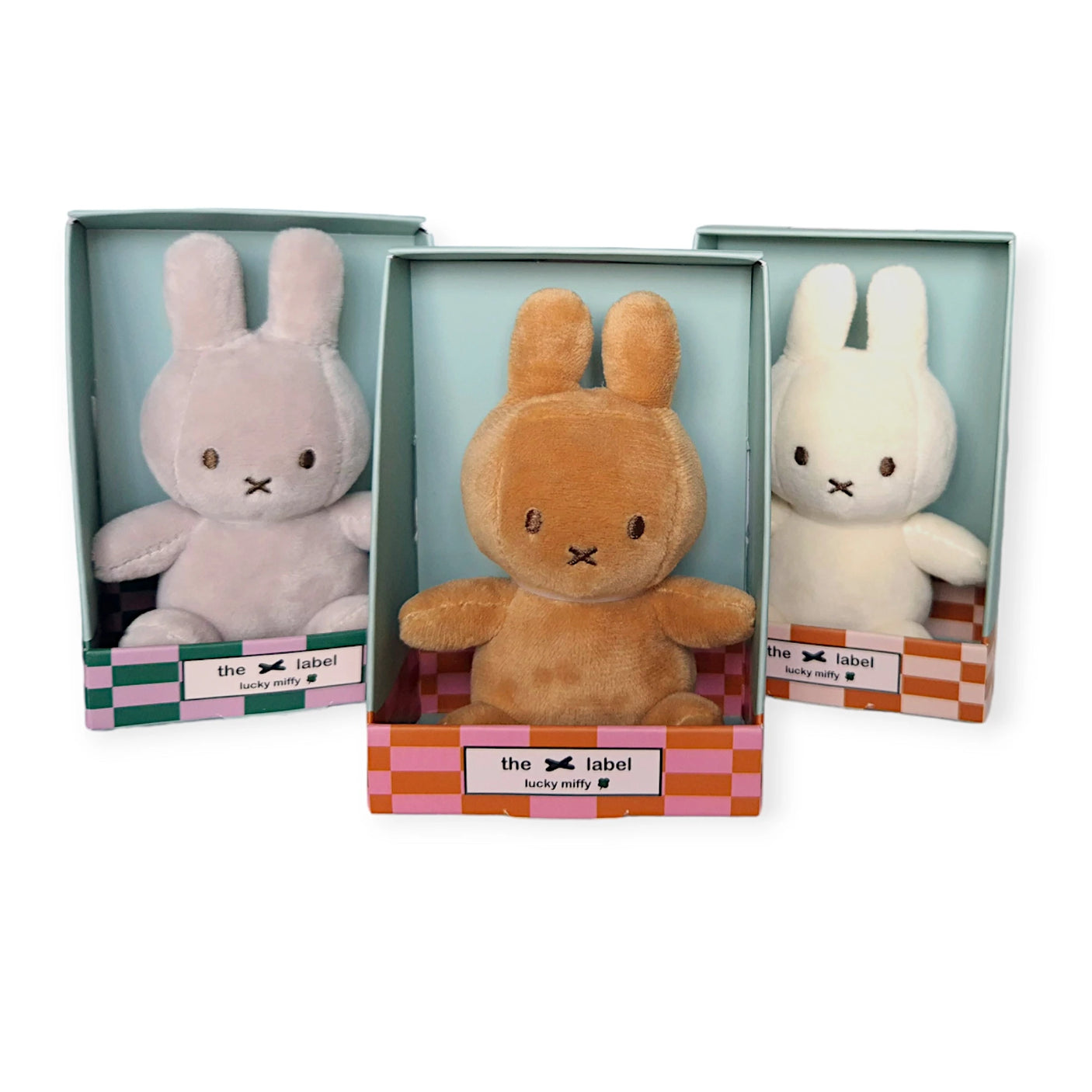 Displayed are three Miffy plush bunny toys in boxes, each a whimsical Mini Miffy Plush. They come in delightful colors: lavender, brown, and white.