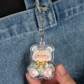 Clear acrylic keychain featuring a round pink pig figure inside a translucent bear-shaped casing with gold bowtie