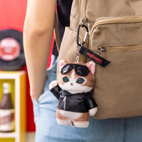 Plush Mofusand cat keychain wearing black leather jacket and sunglasses hanging from beige backpack zipper pull