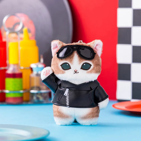 Plush cat keychain with brown and white fur wearing black leather jacket and sunglasses in retro diner setting