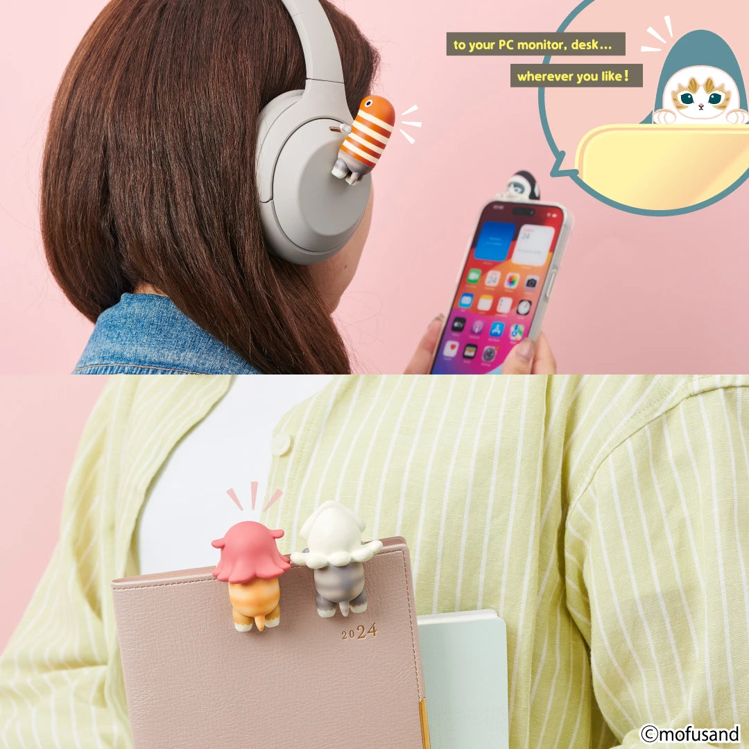 A person wears headphones featuring a striped cat accessory from the Mofusand Hippers Blind Box collection by Mofusand. Two cat-shaped clips are attached to a notebook, ideal for sea-themed characters, while a phone is decorated with a similar playful cat accessory, completing the charming set.