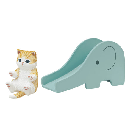 Cat figurine on teal slide, orange-and-white cat with blue eyes.